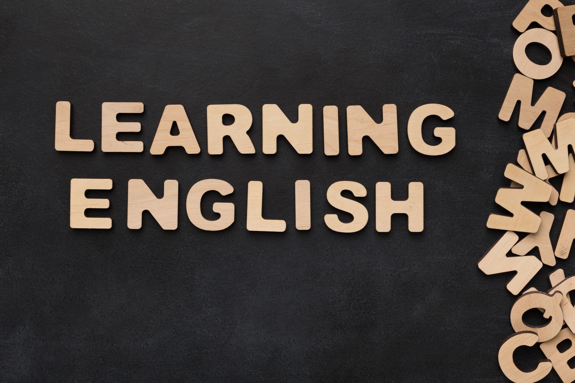 Learning English spelled with wooden letters on black background