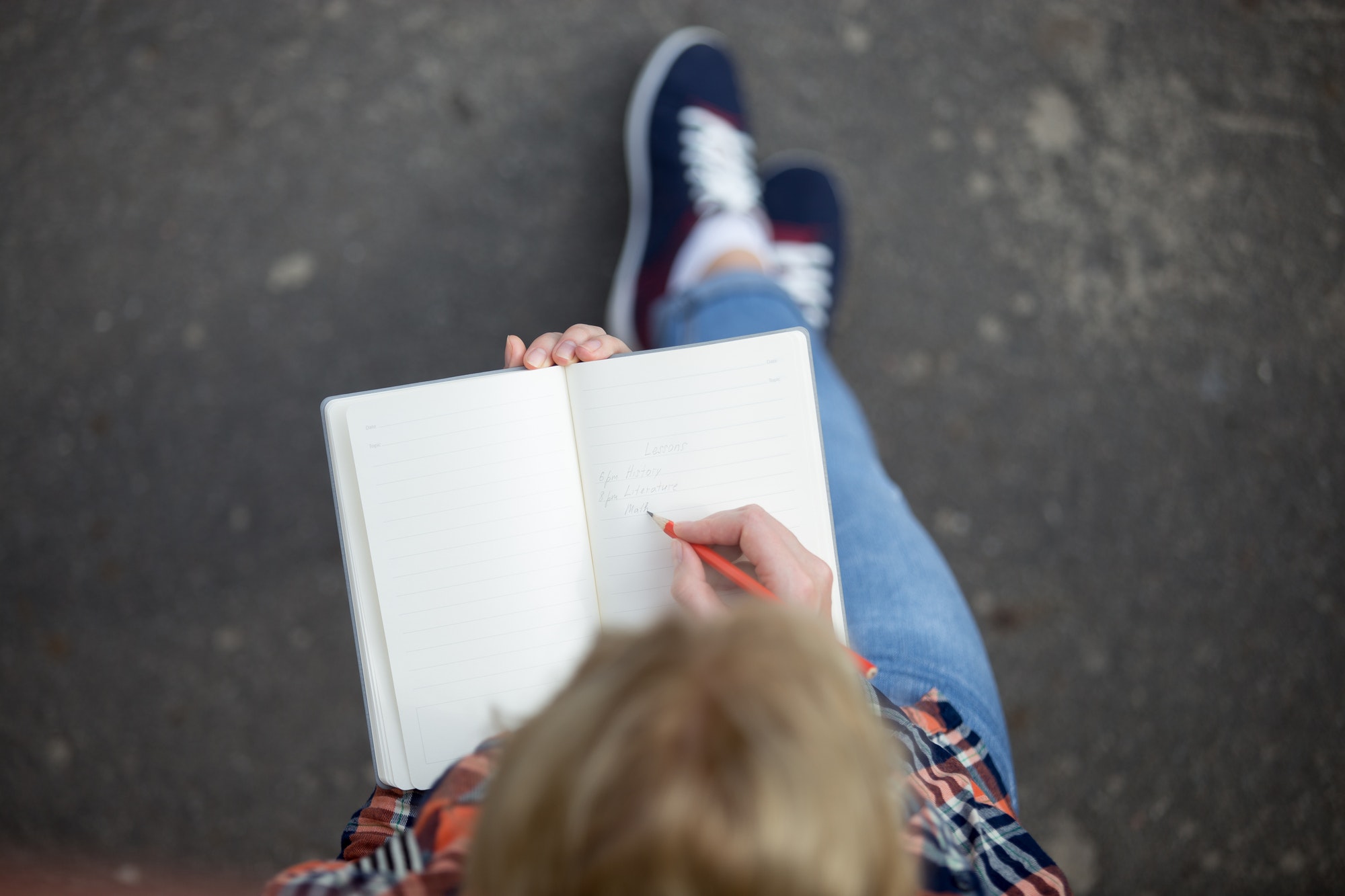 Student girl writing with a pencil in a notebook