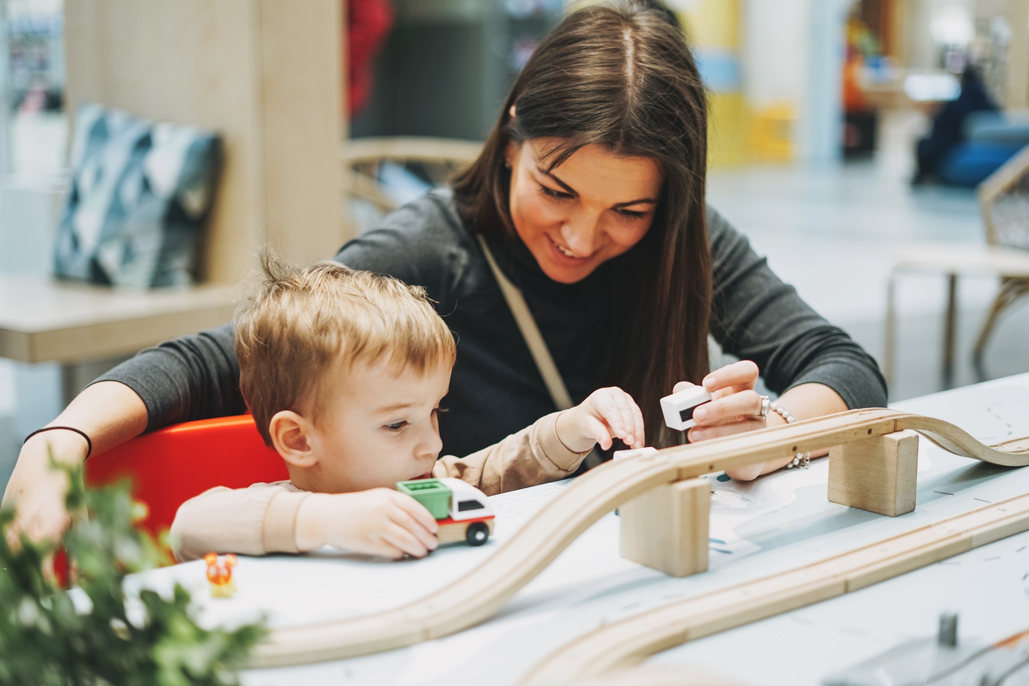 Cute baby boy toddler child with mother play with car toys in game room