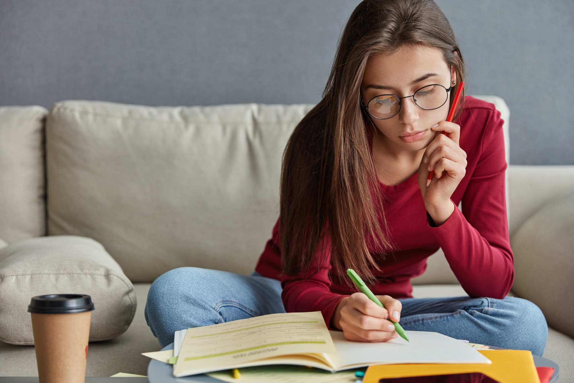 Shot of serious skilled student with pen in hand, writes curriculum vitae, wants to find extra job,